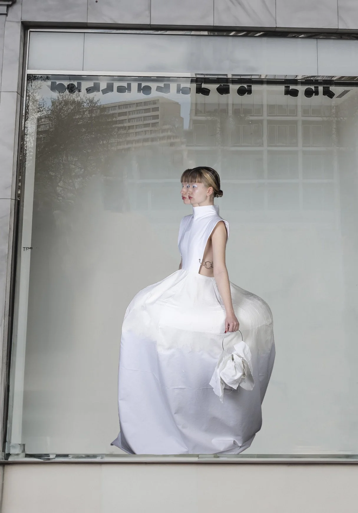 Mural con imagen de una mujer en un vestido blanco con una estructura en forma de globo en la parte inferior, que parece estar en una vitrina o ventana con reflejo de edificios en el fondo.
