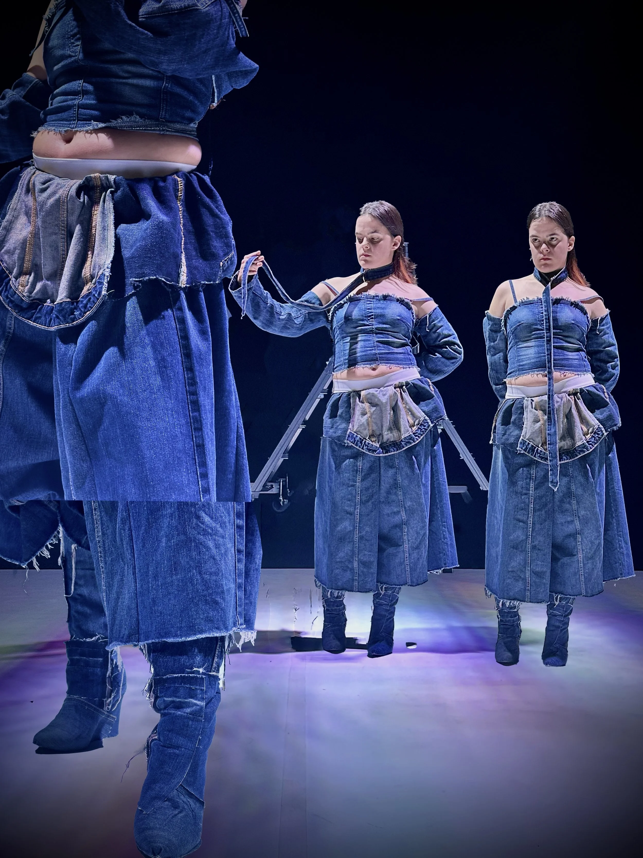 Tres personas con ropa de mezclilla en un escenario oscuro, una de ellas sosteniendo una cuerda, parecen estar en una actuación o presentación teatral.