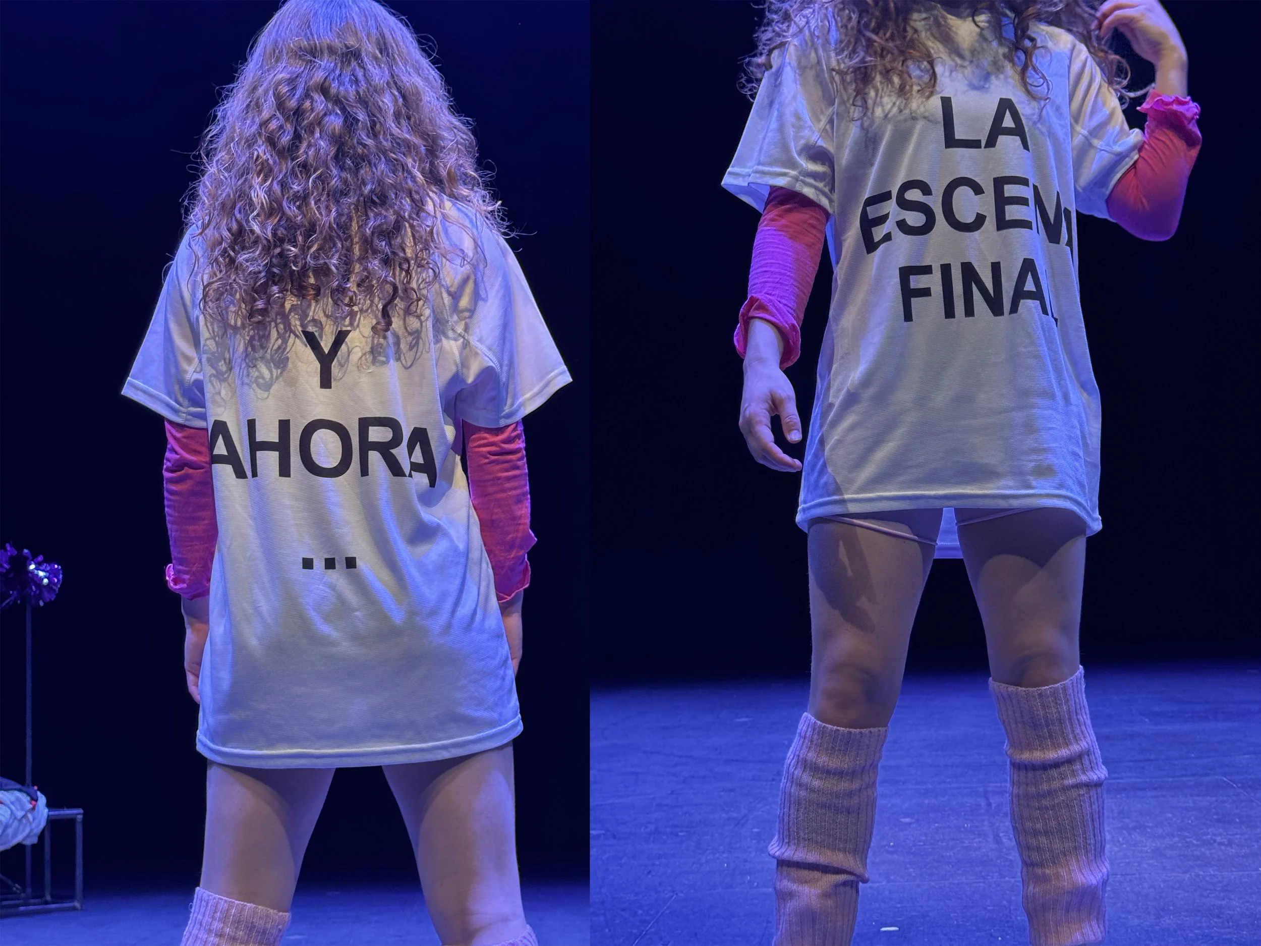 Dos mujeres con camisetas blancas y letras en español, en un escenario con iluminación azul oscuro, de espaldas.