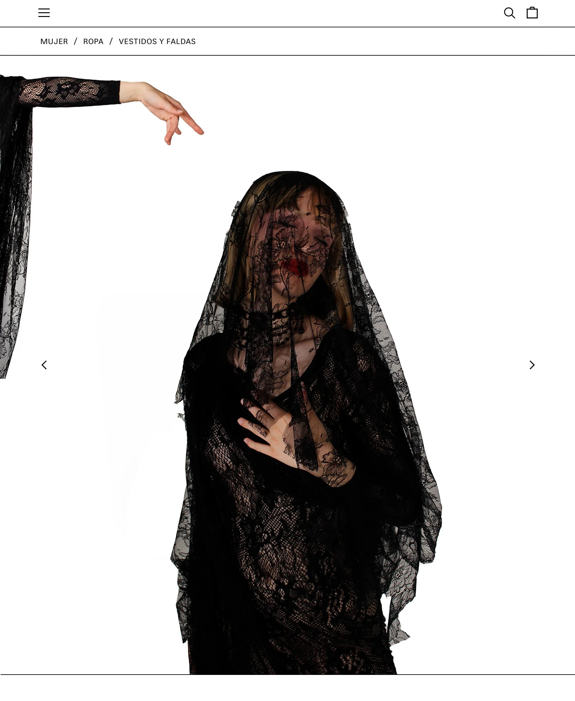 Mujer con vestido negro y encaje, cubierta con una tela negra transparente con detalles florales, sosteniéndose la mano en la cintura y cubriéndose parcialmente con la tela.