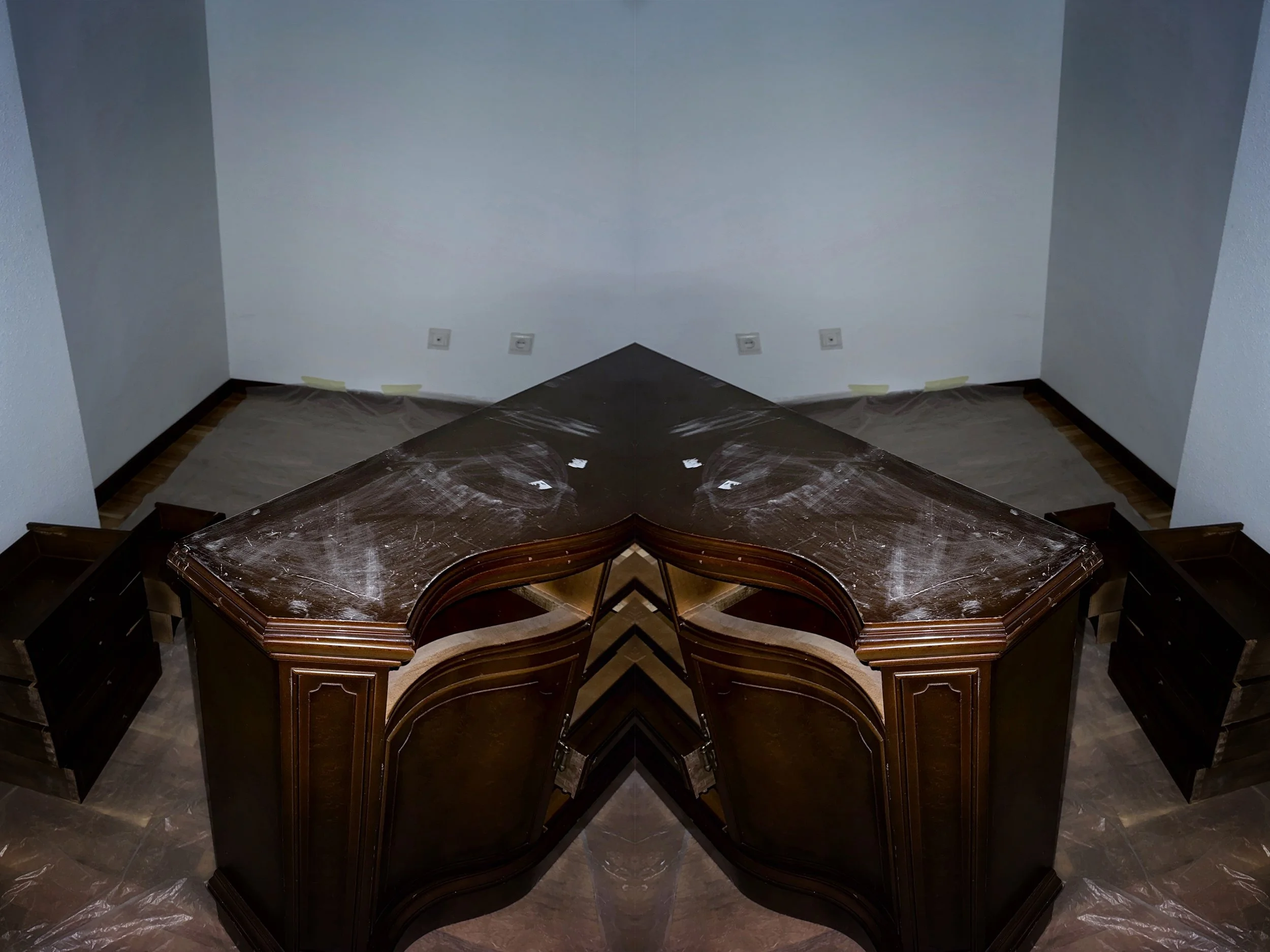 Mesa de madera oscura en un piso de mármol, con marcas de polvo blanco y cinta adhesiva en la pared detrás.