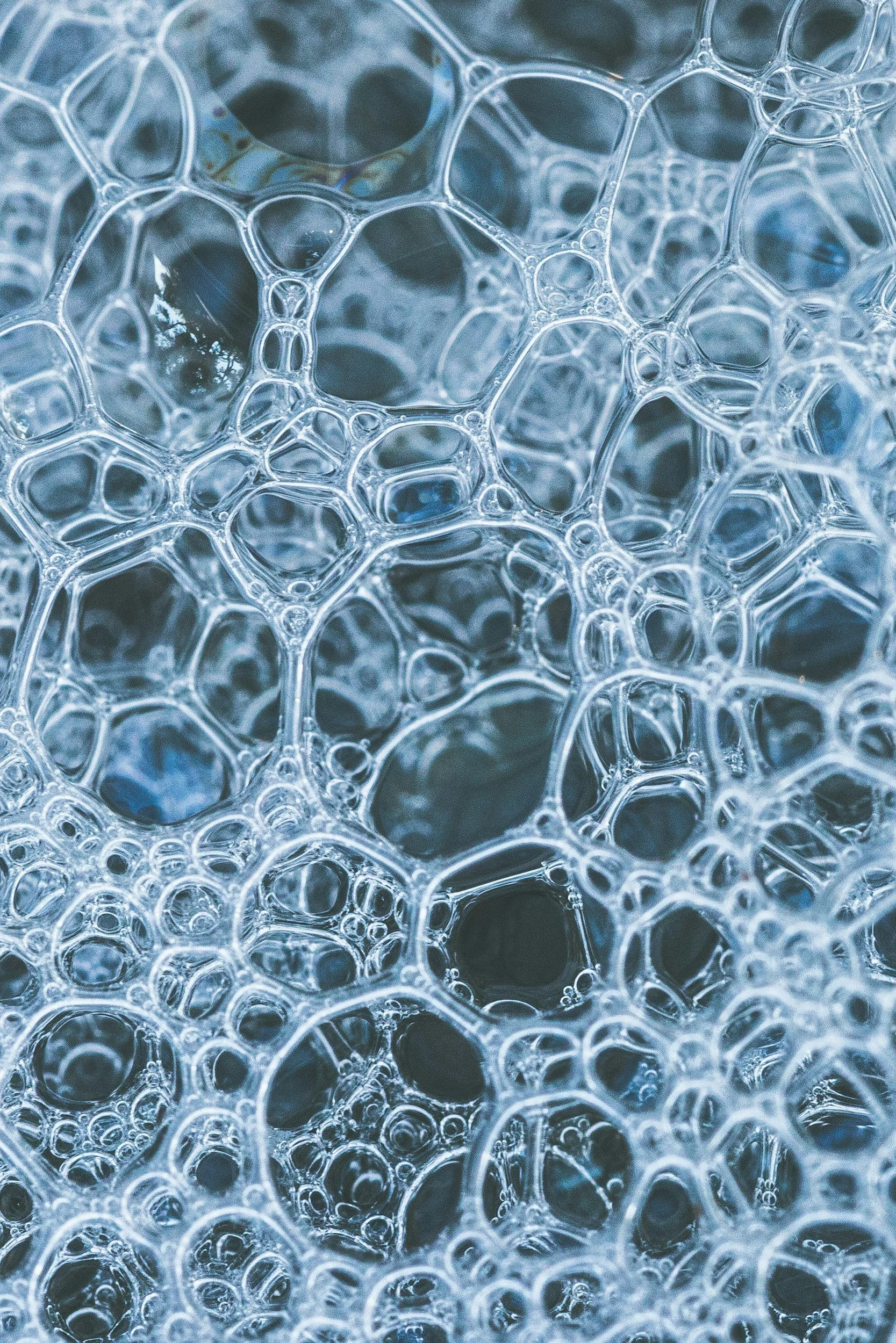 Close-up of numerous overlapping soap bubbles with a bluish tint.