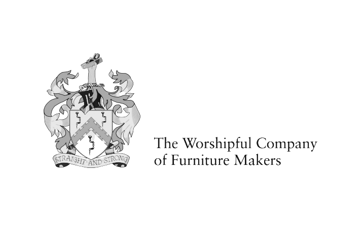 Logo for The Worshipful Company of Furniture Makers, featuring a coat of arms with a shield and a banner reading 'Straight and Strong'.