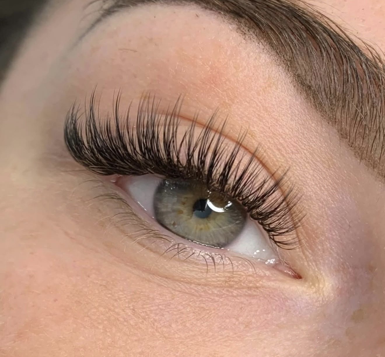 Close-up of a person’s eye with long, thick eyelashes and well-groomed eyebrows.