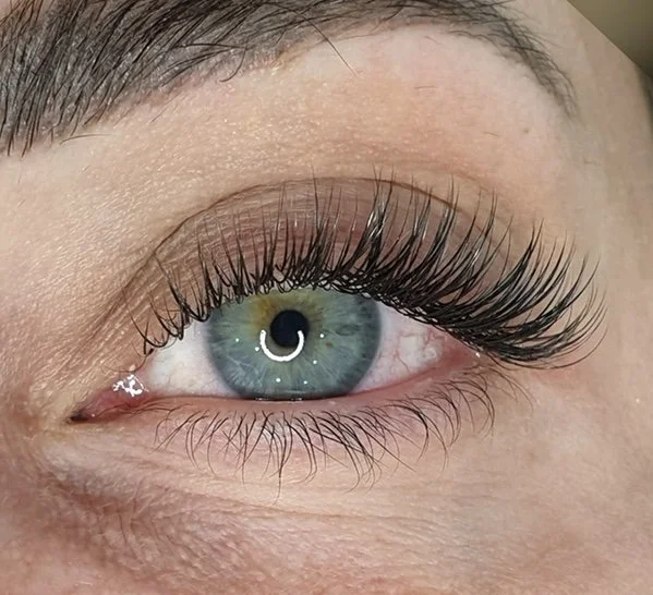 Close-up of a blue-green eye with long, dark eyelashes and a well-groomed eyebrow.