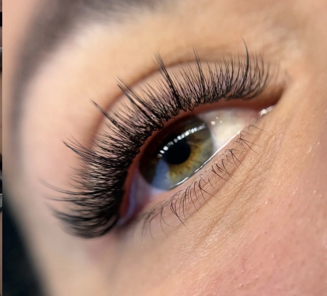 Close-up of a human eye with long, curled eyelashes and a hazel iris.