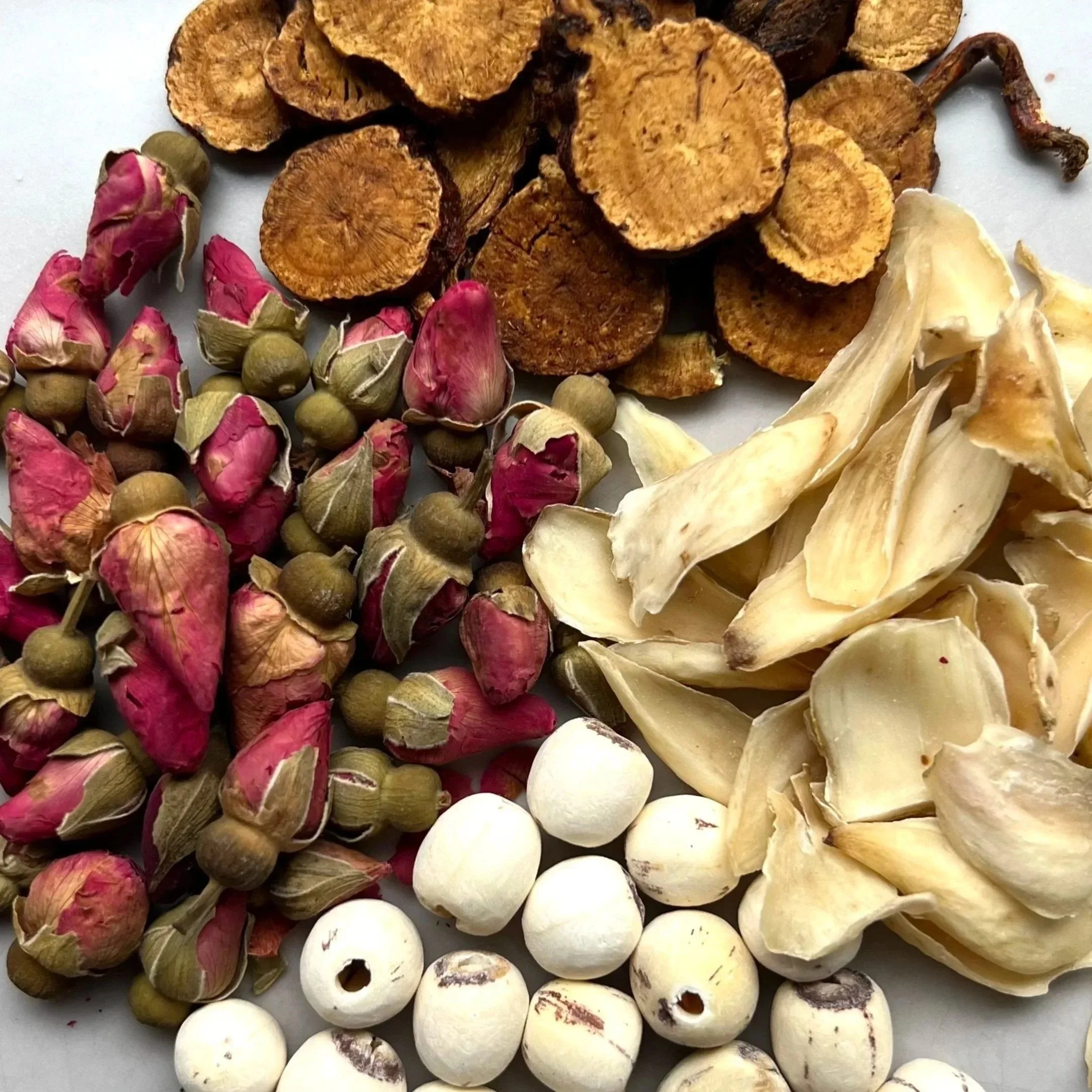 Selection of dried Chinese medicinal herbs, roots, seeds and rose buds traditionally used in Chinese herbal medicine.