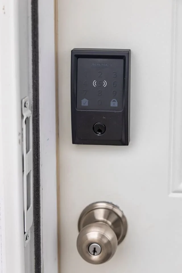 A door with a digital keypad lock system above a round metal doorknob with a keyhole.