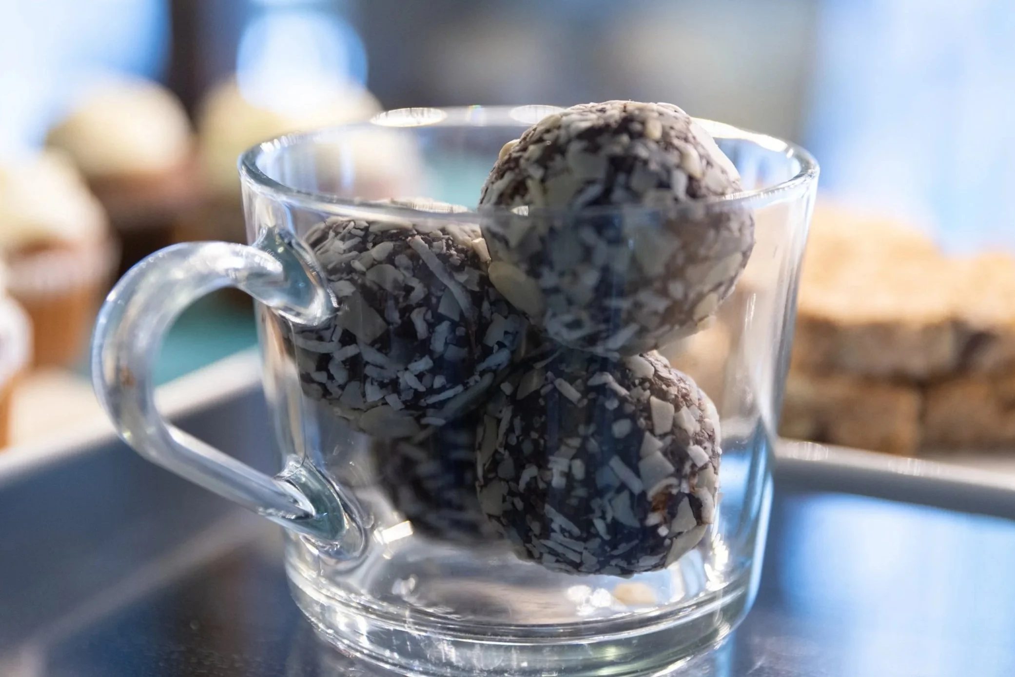 Clear espresso glass holding 3 coconut covered energy balls At Fancy Pants Cafe in Bridgewater, Nova Scotia