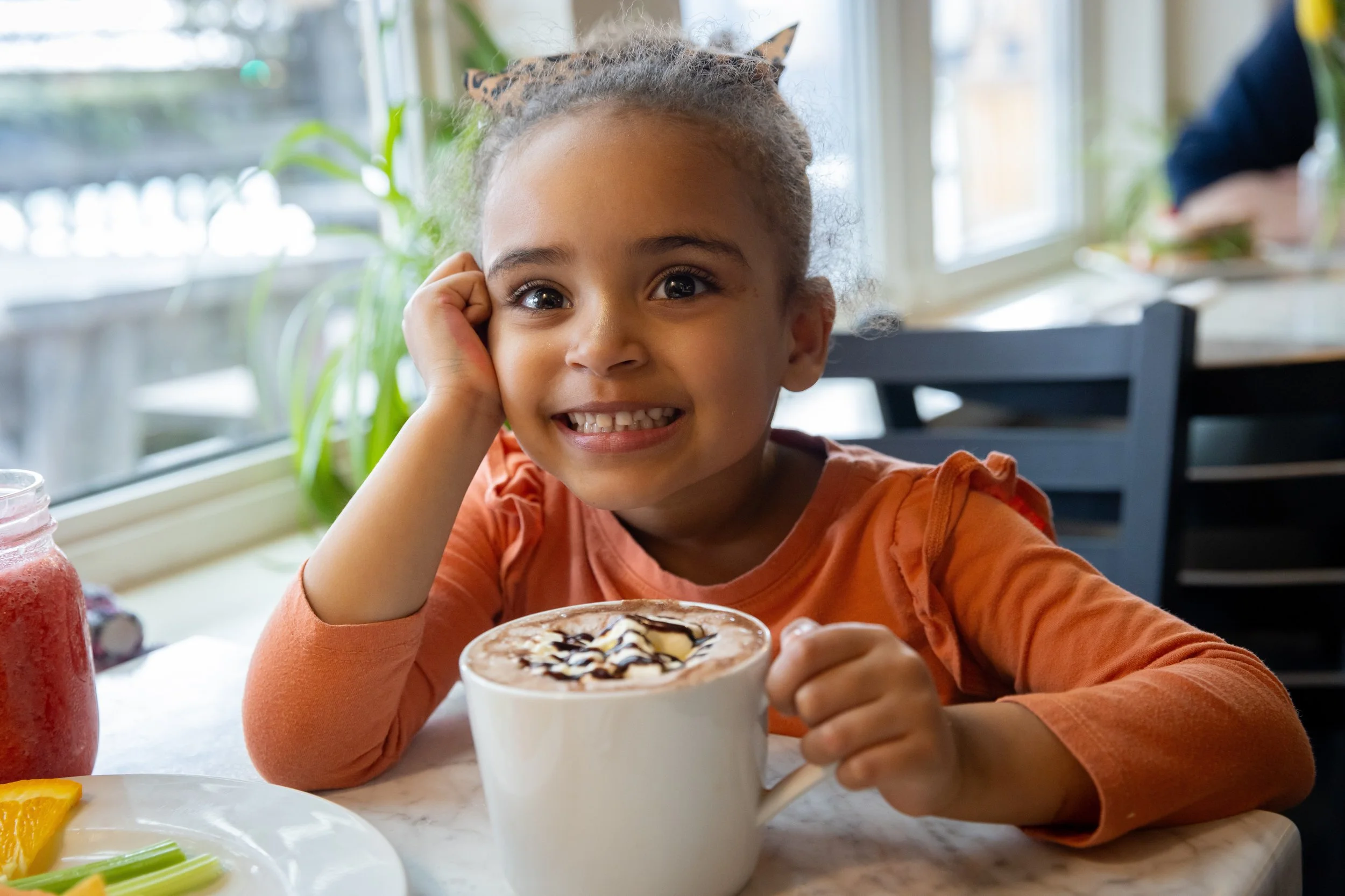A young child smiles at the camera with a cup of hot cocoa At Fancy Pants Cafe in Bridgewater, Nova Scotia