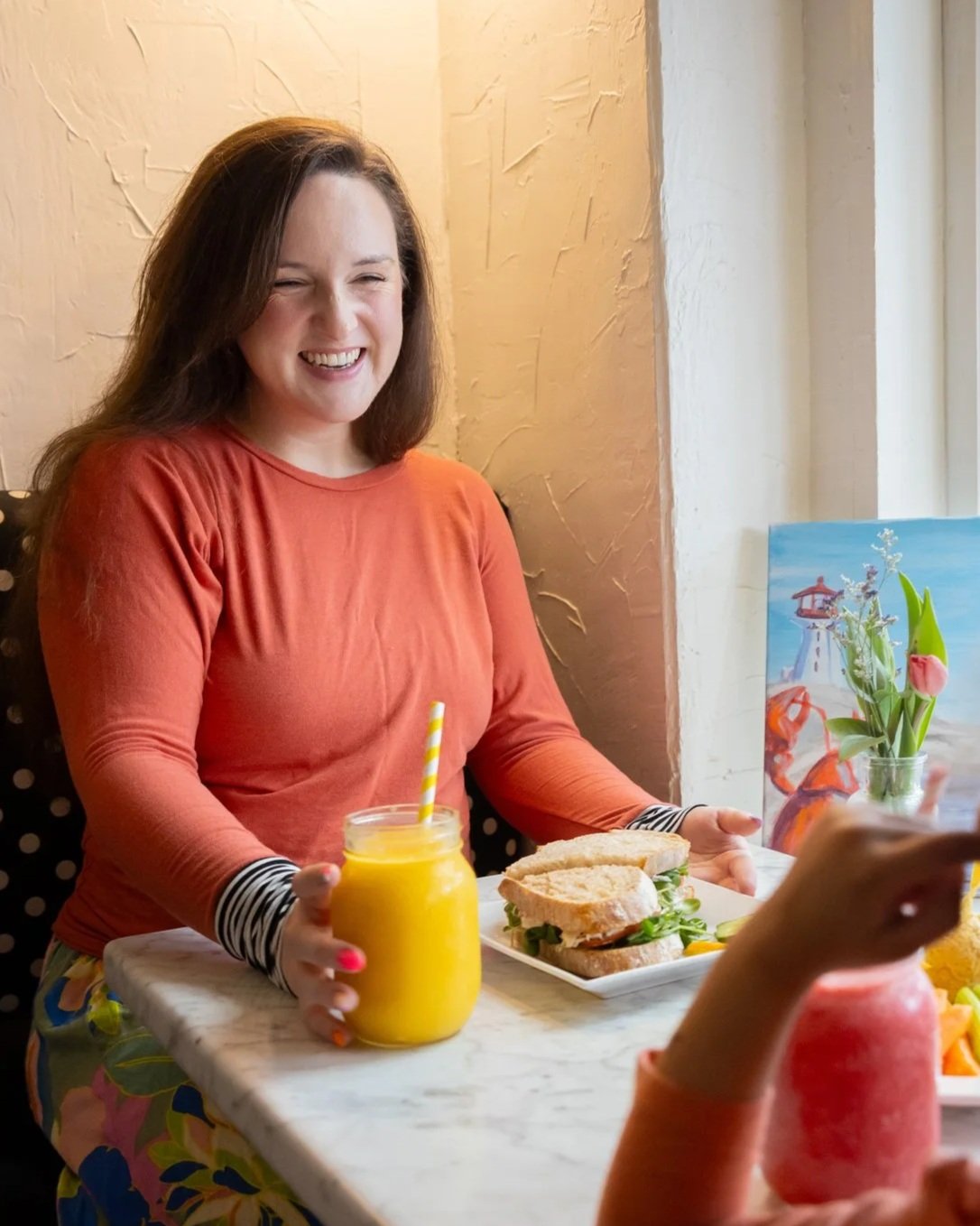A customer smiles while holding a yellow smoothie during a meal at Fancy Pants Cafe in Bridgewater, NS