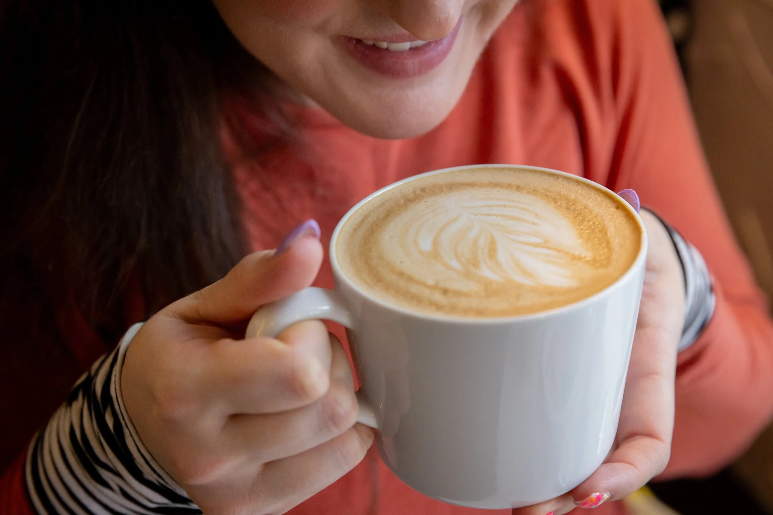 Close up of a woman sipping a latte out of a mug At Fancy Pants Cafe in Bridgewater, Nova Scotia