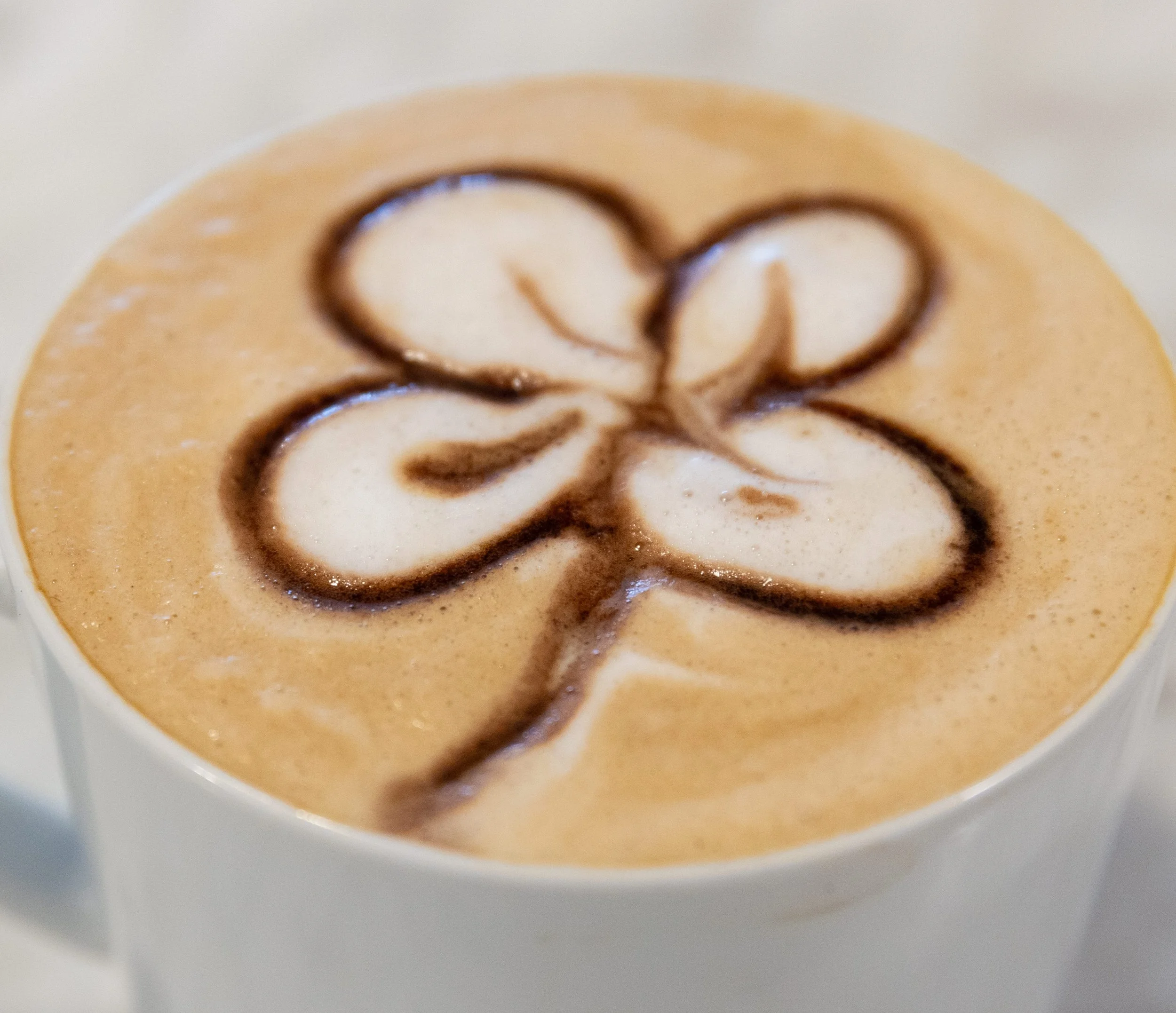 Latte with flower or shamrock made of chocolate syrup At Fancy Pants Cafe in Bridgewater, Nova Scotia