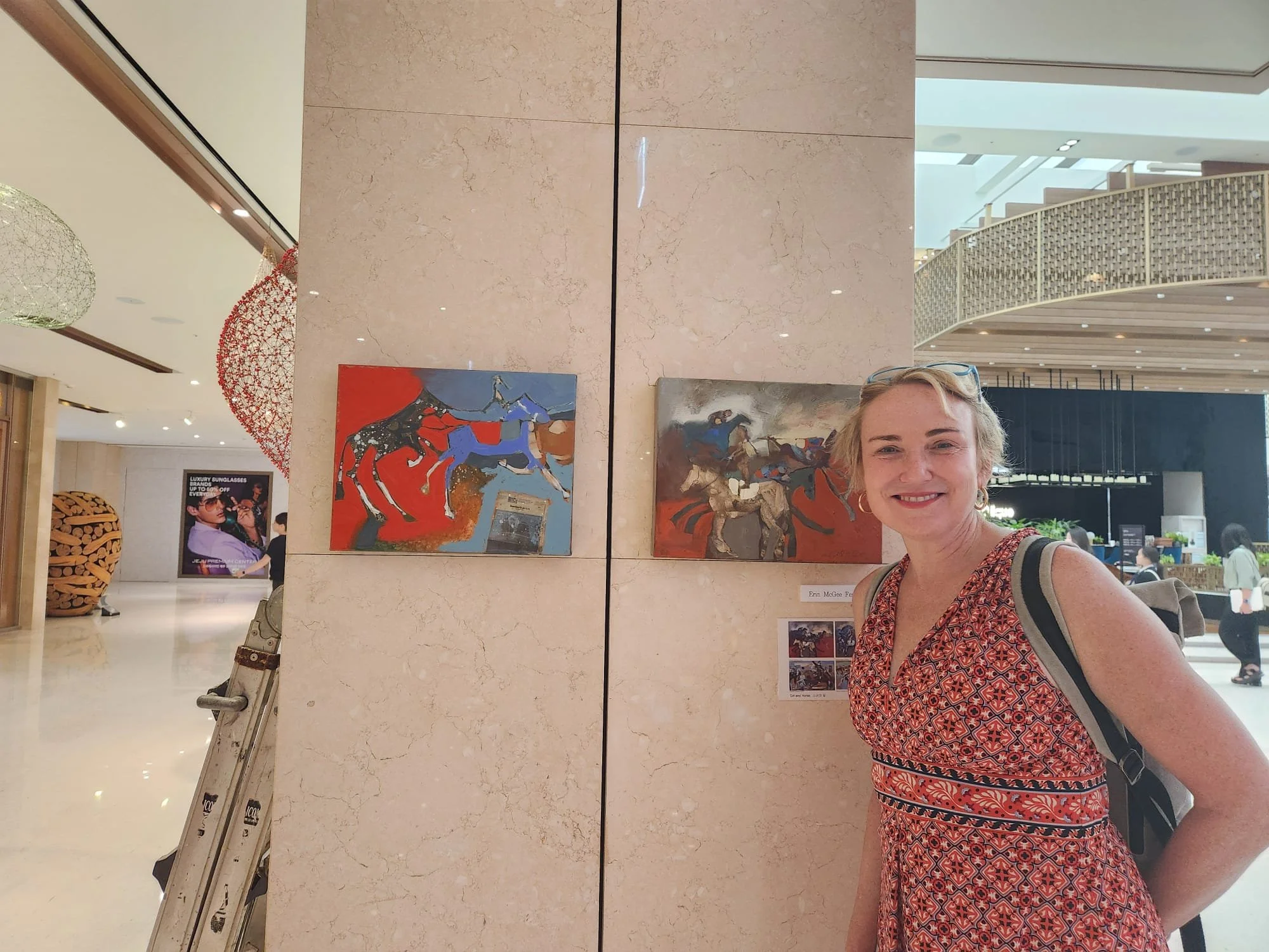 Erin McGee Ferrell beside her horse paintings in the Jeju Art for Earth exhibition at Jeju Shinhwa World, South Korea, 2025.