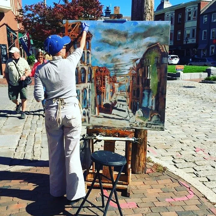 Erin McGee Ferrell painting on a cobblestone street.