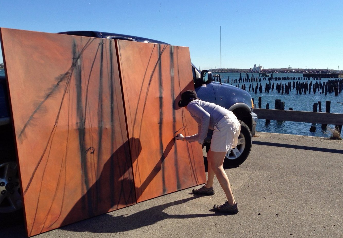 Erin McGee Ferrell working outdoors on a large canvas beside the waterfront.