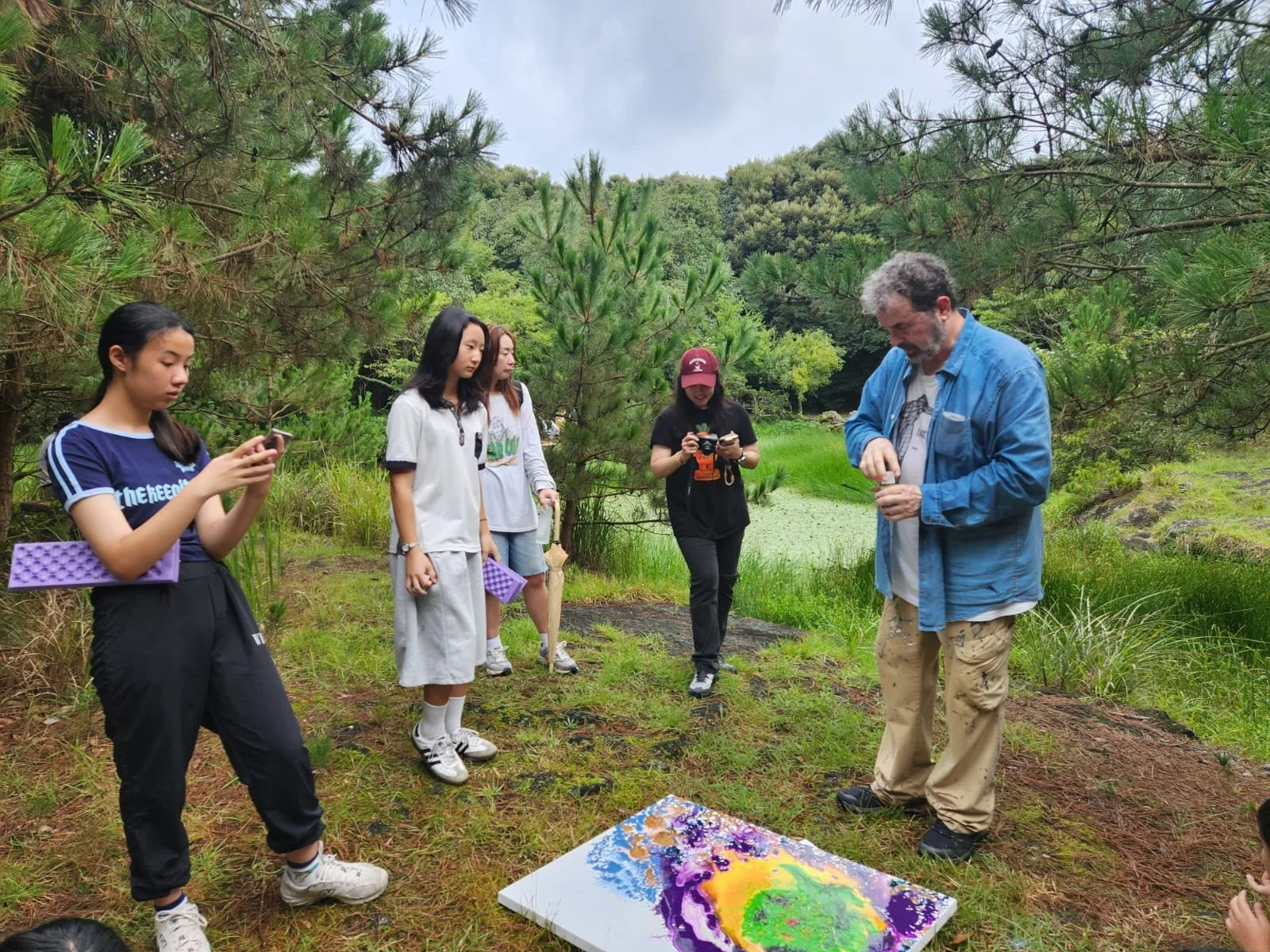 Young participants observe a painting demonstration during the Jeju Art for Earth community program at Dongbaekdongsan, South Korea, 2025.