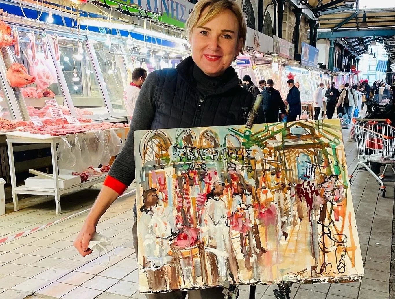 Erin McGee Ferrell with her painting in an Athens market, 2022.