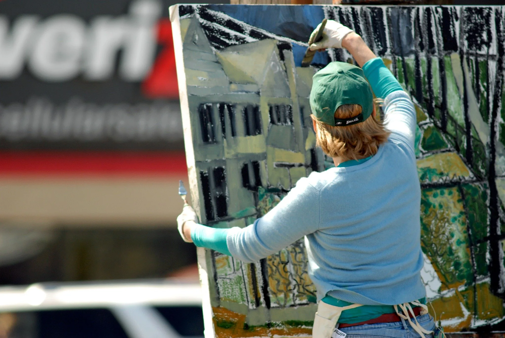 Working directly on a large architectural painting outdoors.
