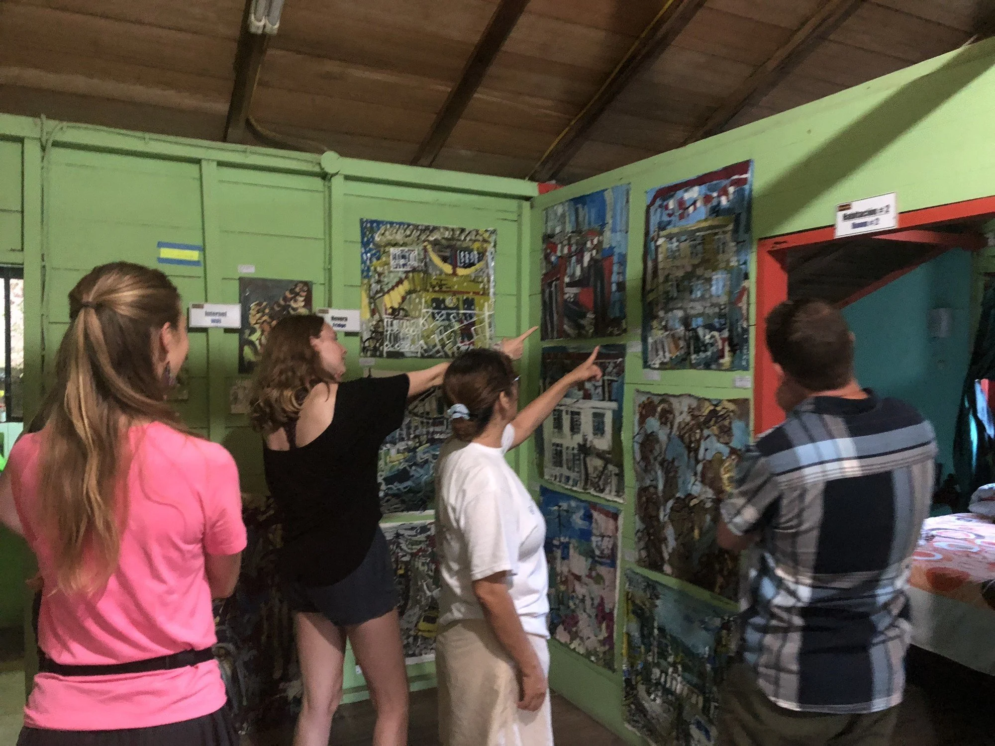 Visitors discussing Erin McGee Ferrell’s Ecuador paintings displayed together in Tena.