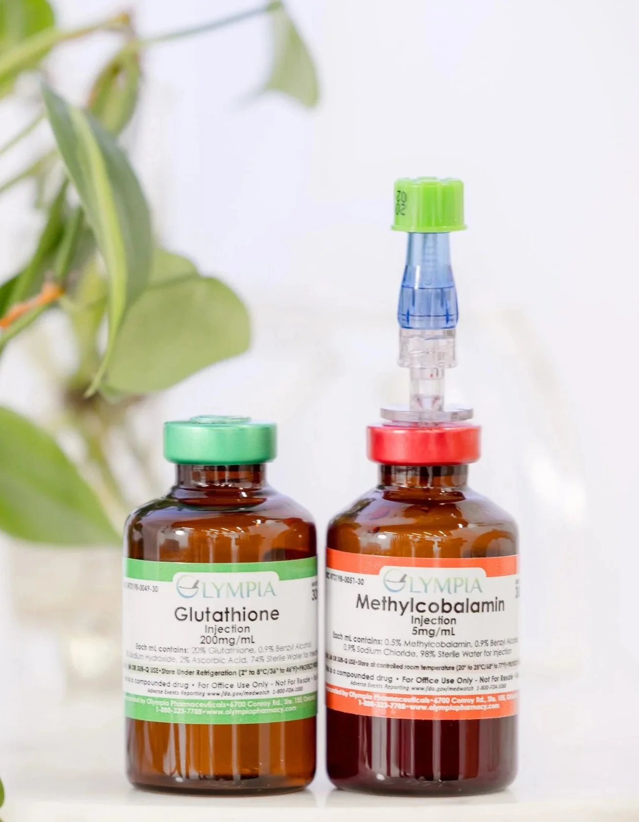 Two small brown medicine bottles with labels, one labeled Glutathione and the other Methycobalamin, placed on a white surface with some green leaves visible in the background.