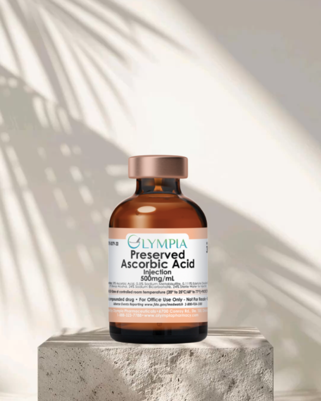 A brown glass vial labeled 'Olympia Preserved Ascorbic Acid Injection 500mg/mL' sitting on a textured surface with a shadow and sunlight pattern in the background.