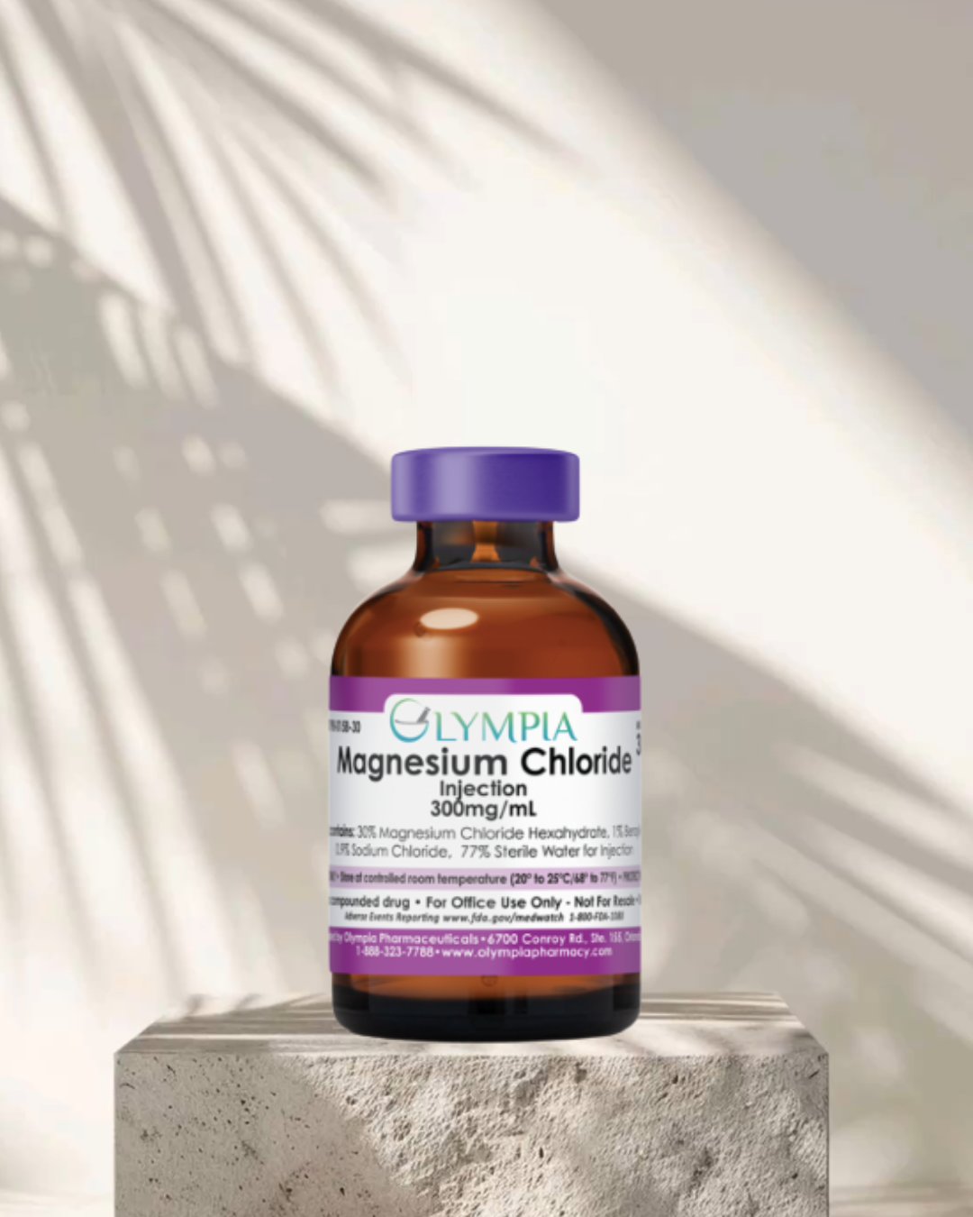 Bottle of Olympia Magnesium Chloride injection 300mg/mL placed on a concrete surface with shadow of a palm leaf on the wall in the background.
