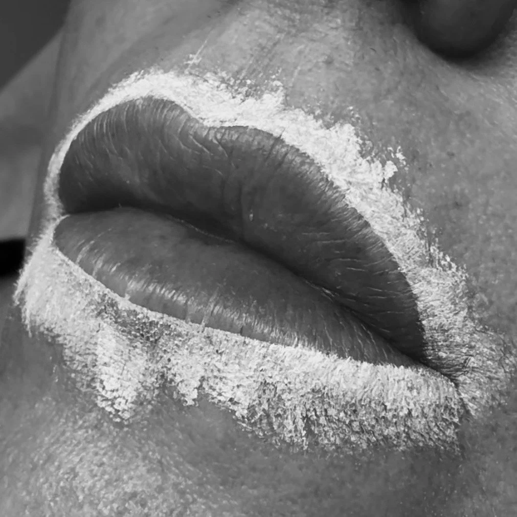 Close-up of lips with white powder around the mouth area in black and white.