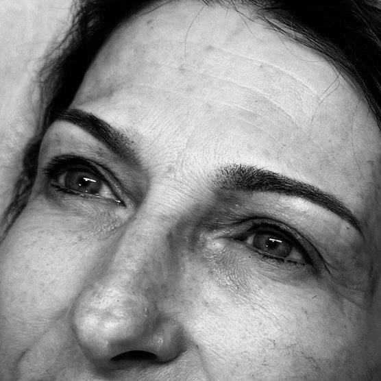 Close-up black-and-white photo of a woman's face, focusing on her eyes and forehead