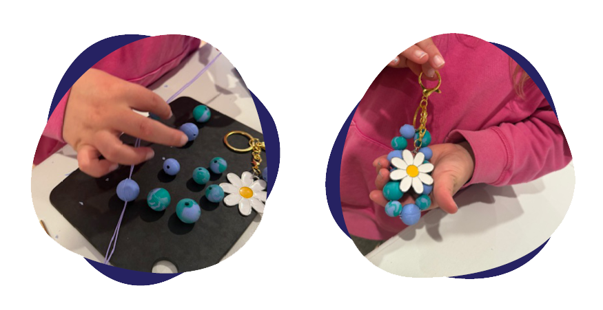 Child making jewelry with blue beads and a flower charm.