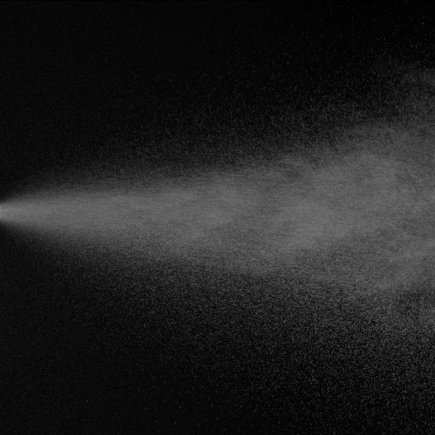 A close-up of a fine mist or spray of water particles illuminated against a dark background, creating a textured, cloud-like appearance.