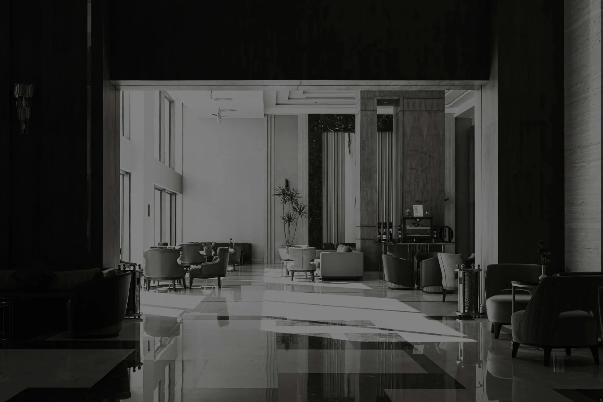 Luxurious hotel lobby with seating area, large windows, modern furniture, and indoor plants.