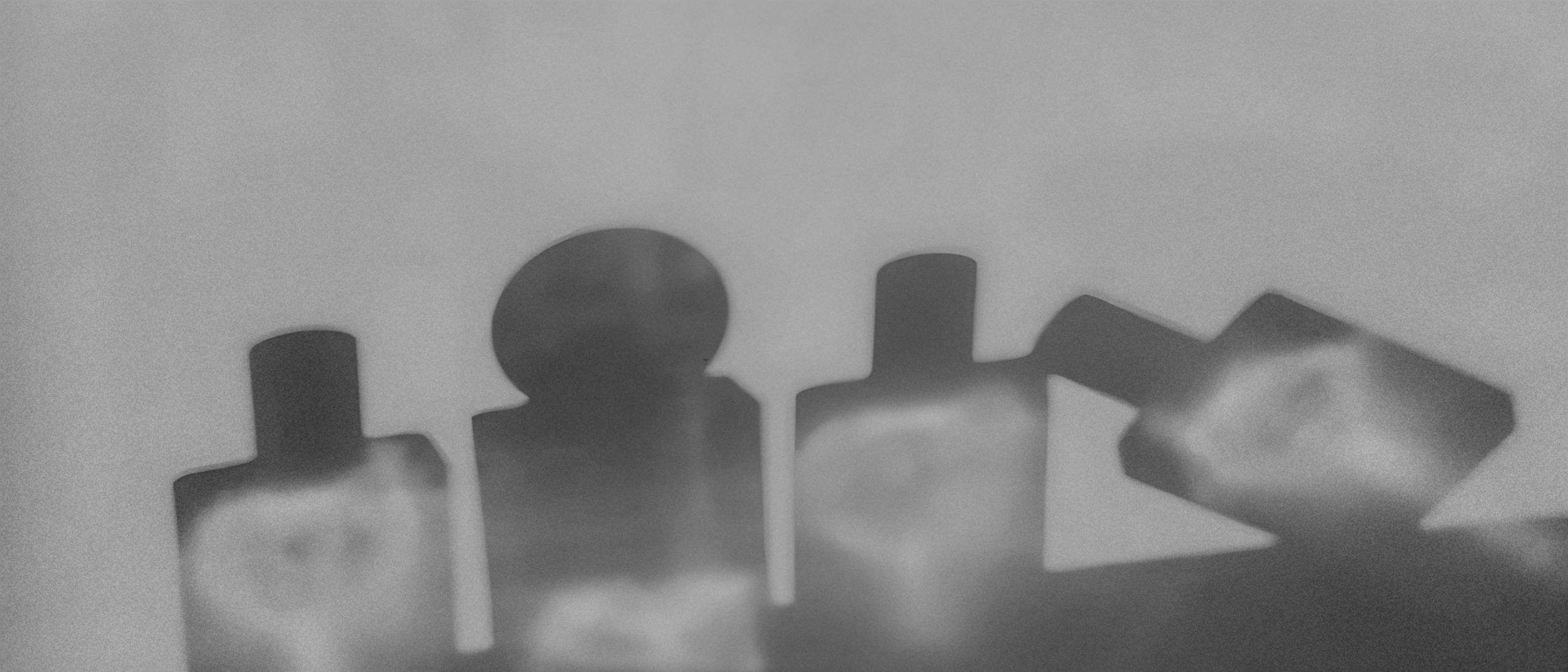 Distributeur automatique de parfums. Flacons de parfums en ombre transparente tous un peu flous, en noir et blanc.