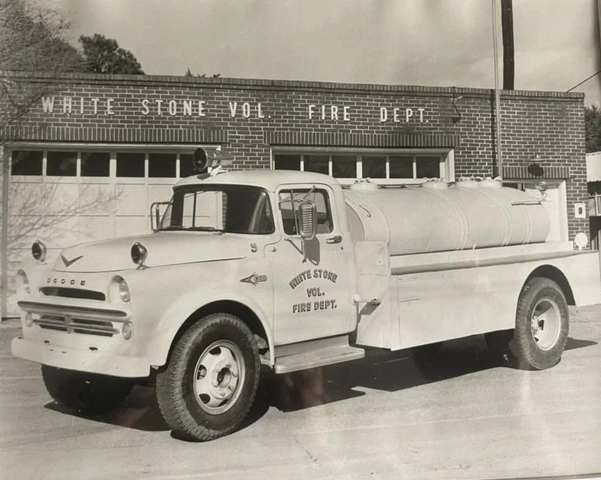 Vintage black and white photo of a White Stone Volunteer Fire Department fire truck parked outside a brick fire station building.