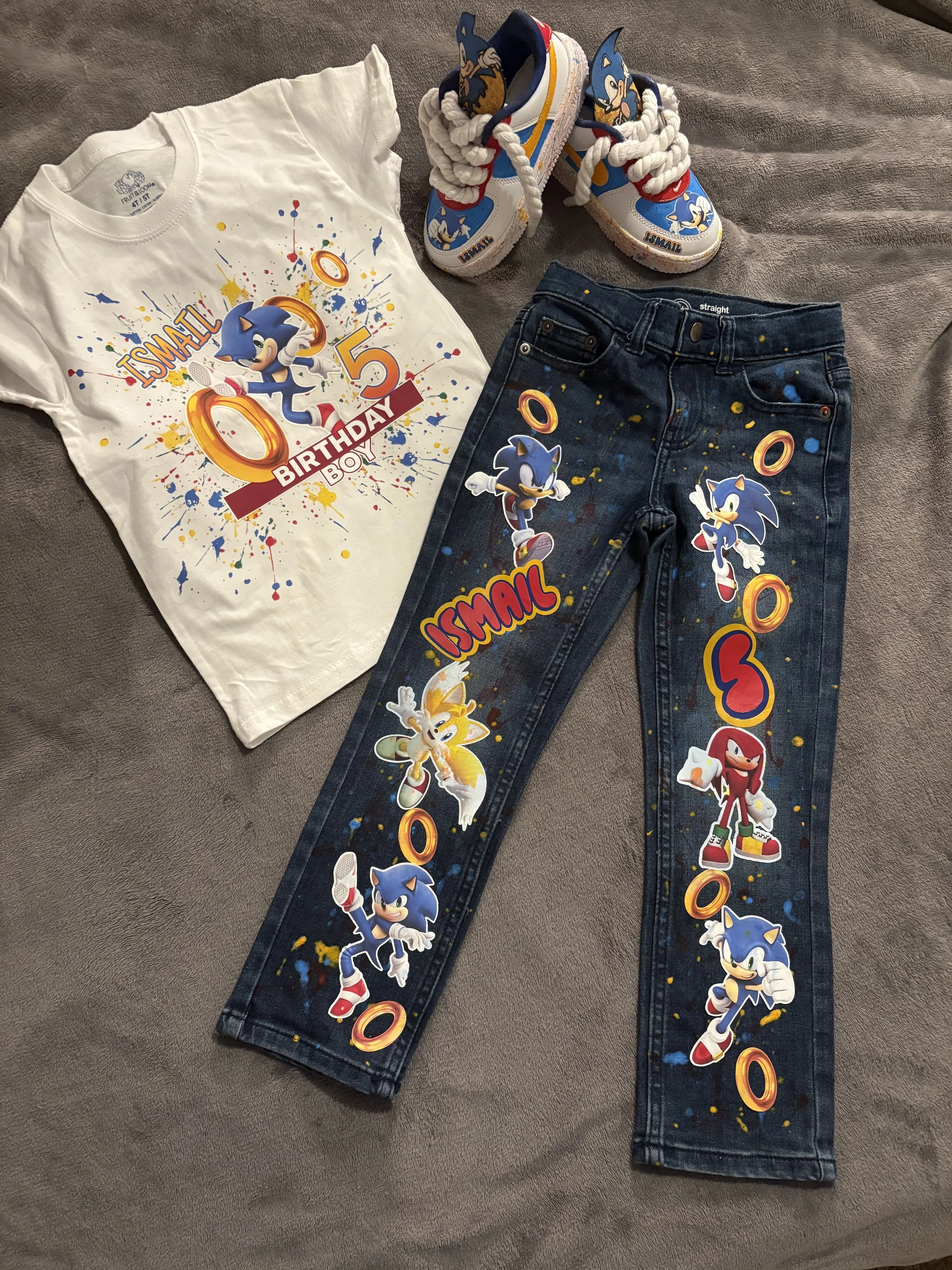 Sonic the Hedgehog birthday outfit set including a white T-shirt, dark jeans, and matching sneakers, all decorated with Sonic and friends graphics and colorful paint splatters.