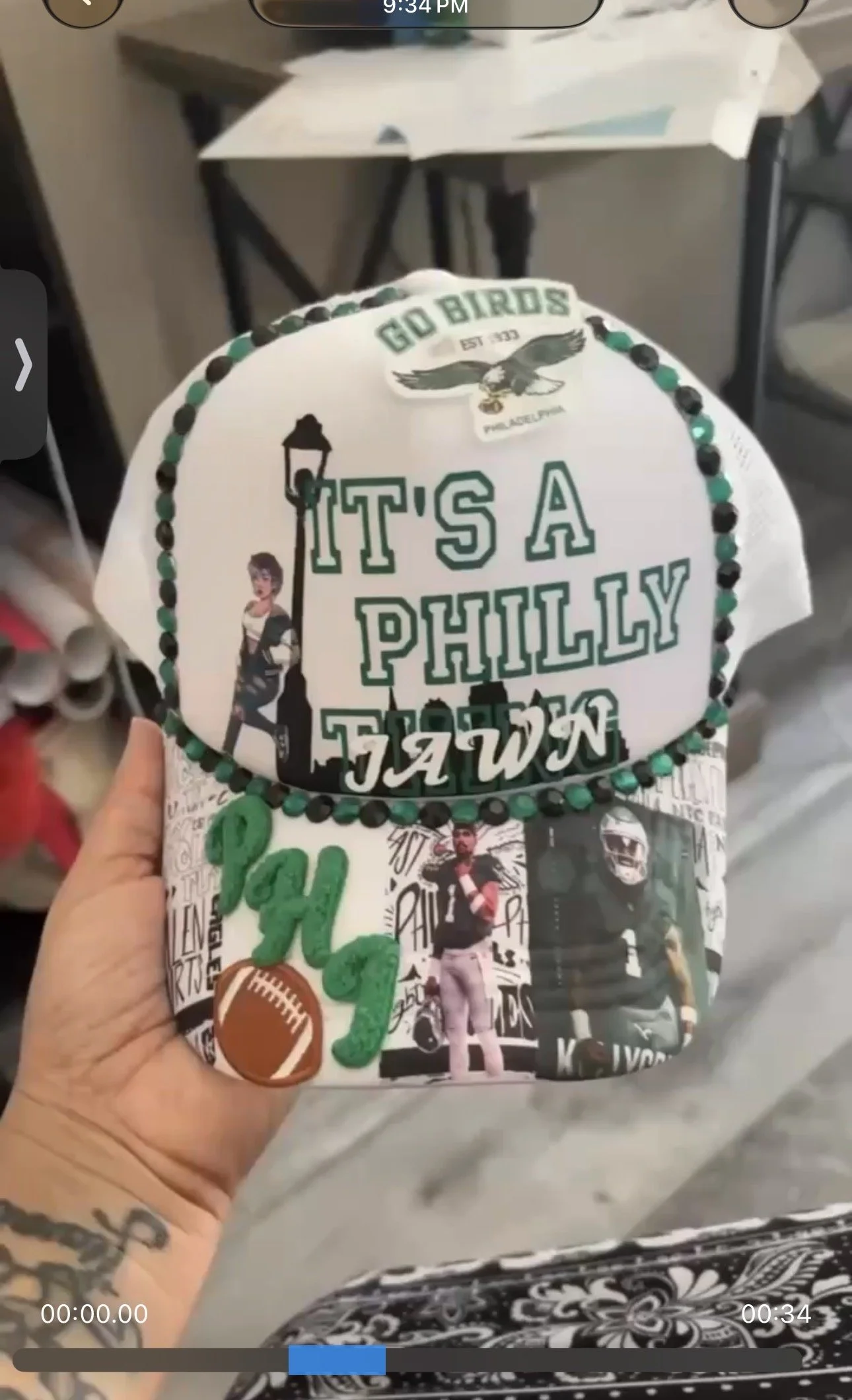 A decorative hat with various images and text, including a sticker of an eagle, a sticker that says "Go Birds" with an eagle graphic, the phrase "It's a Philly Thing," a football graphic, and photos of a man in different poses.