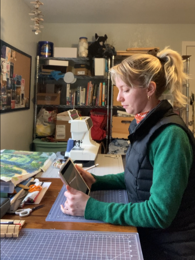 Freyja working on her iPad at her studio table in her artpartment.