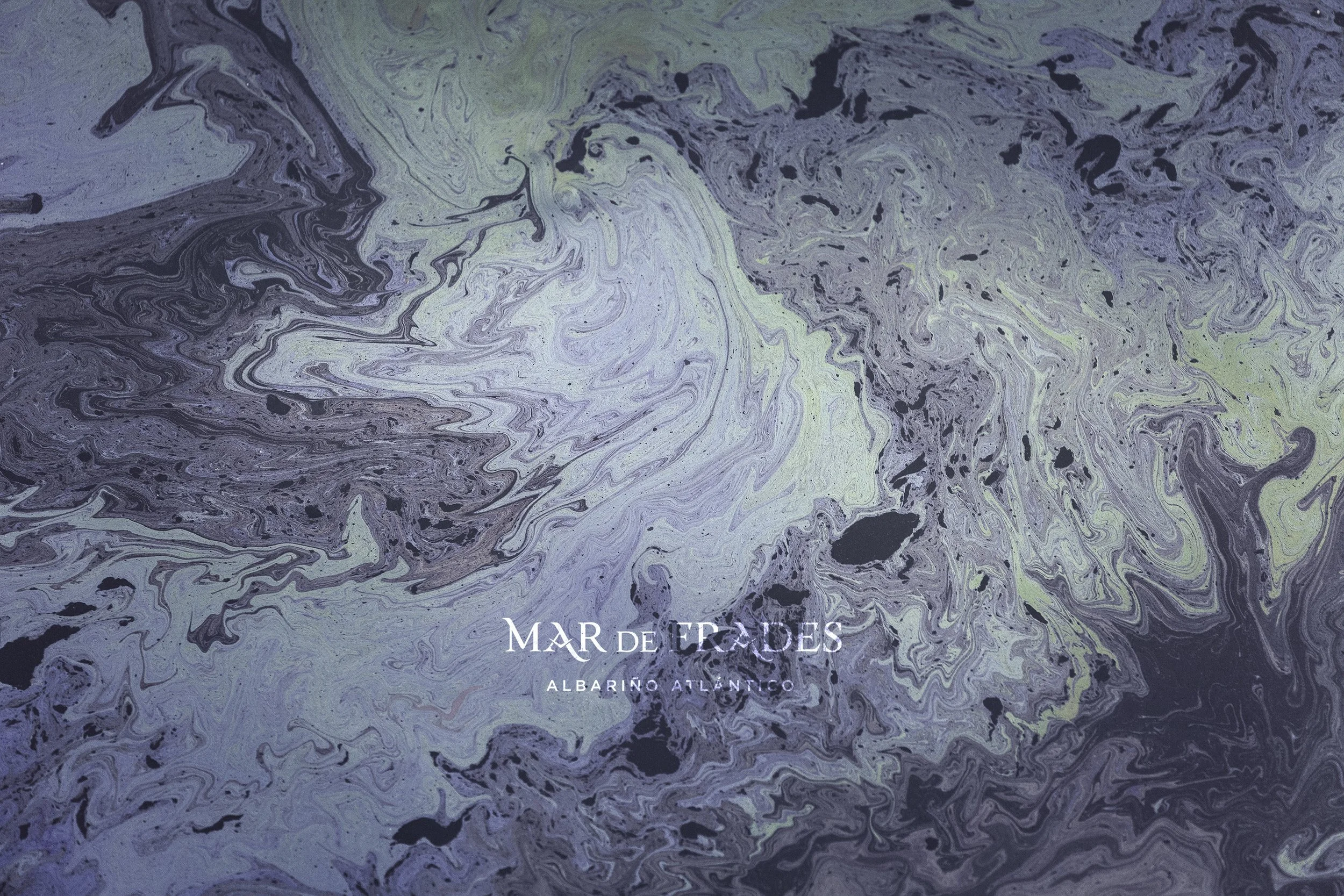 Abstract marbled background in shades of purple, green, and black, with white text that reads 'MAR DE TRADAS ALBARIÑO ATLÁNTICO'.