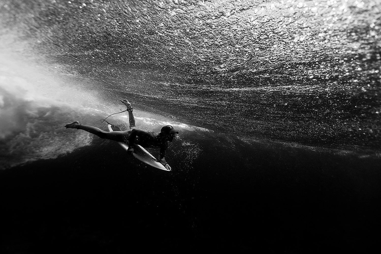 A person surfing on a wave in black and white.