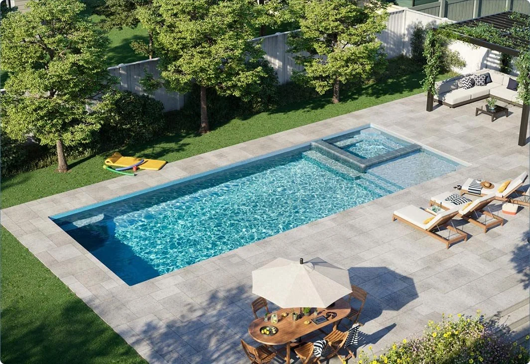 A backyard with a modern rectangular swimming pool, hot tub, and tiled patio. There are poolside lounge chairs, a table with an umbrella, and some outdoor seating.