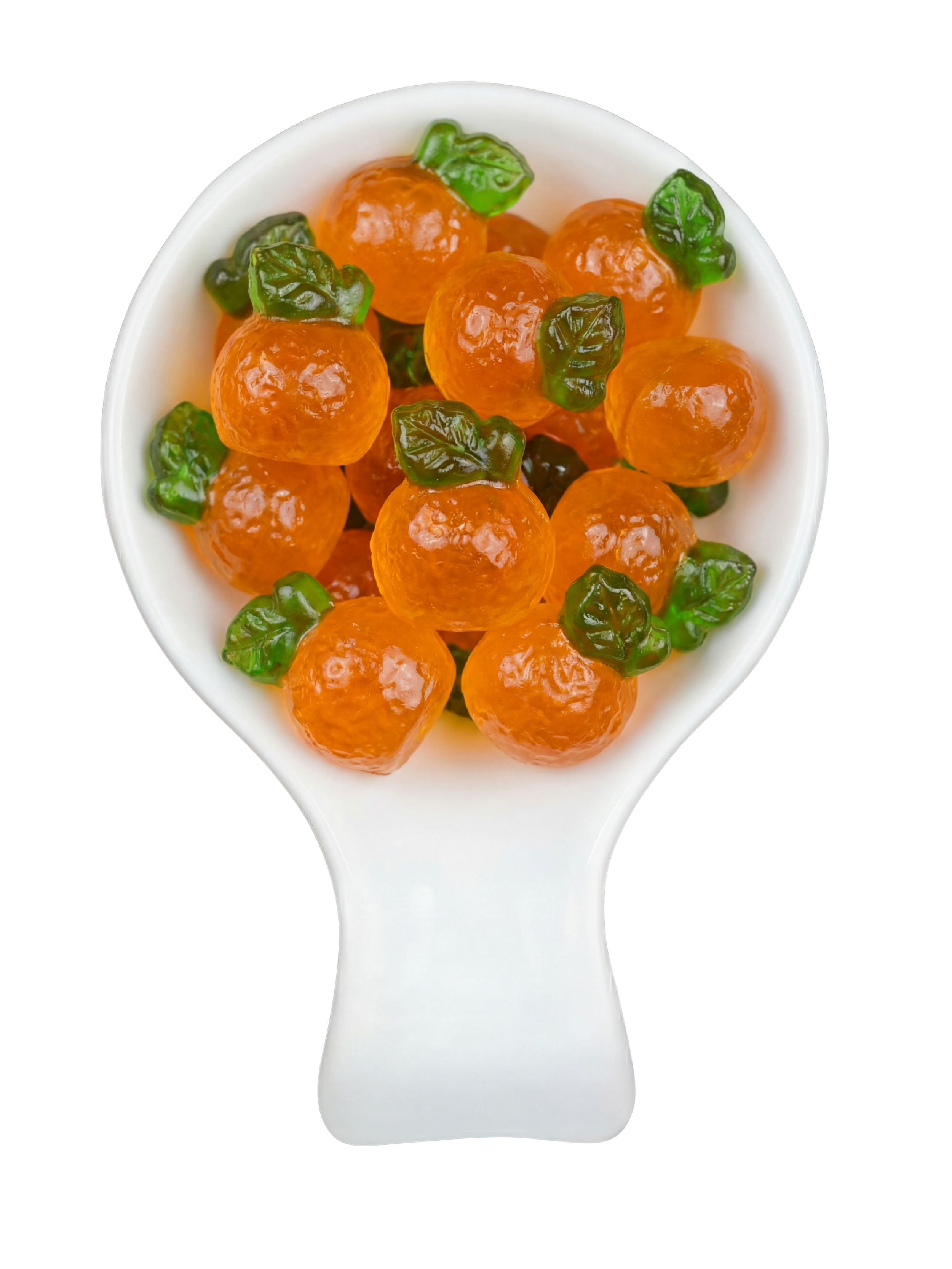 A white spoon filled with orange spherical candies topped with green candy leaves, set against a black background