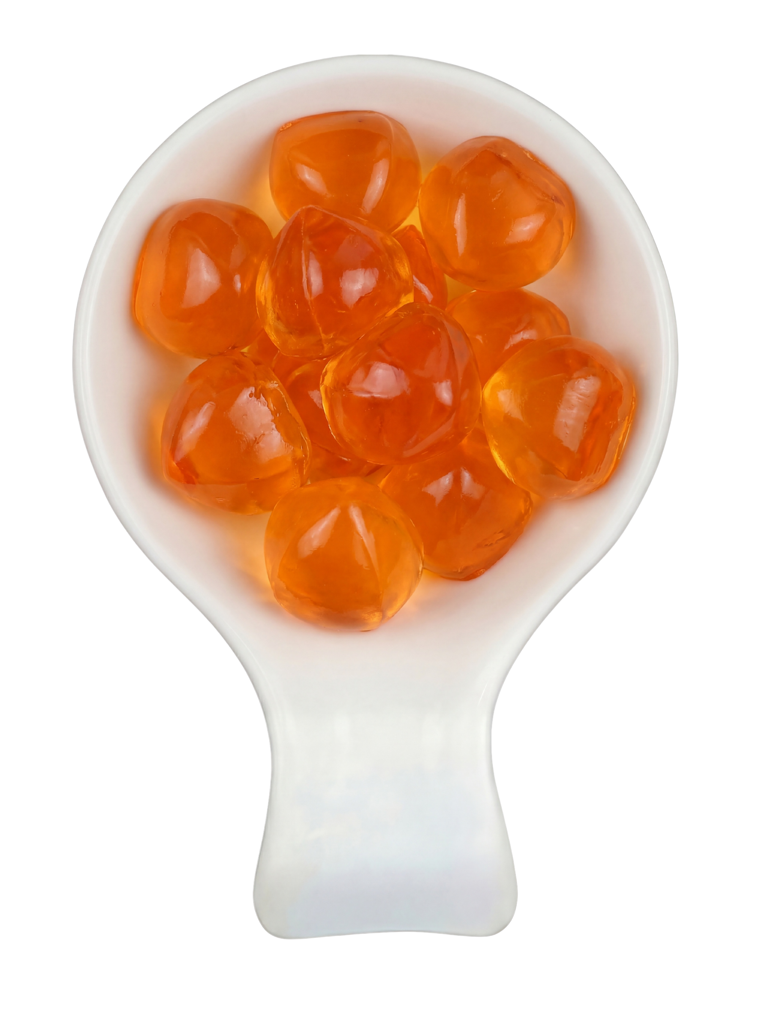 Close-up of orange chewing candies in a white spoon against a dark background.