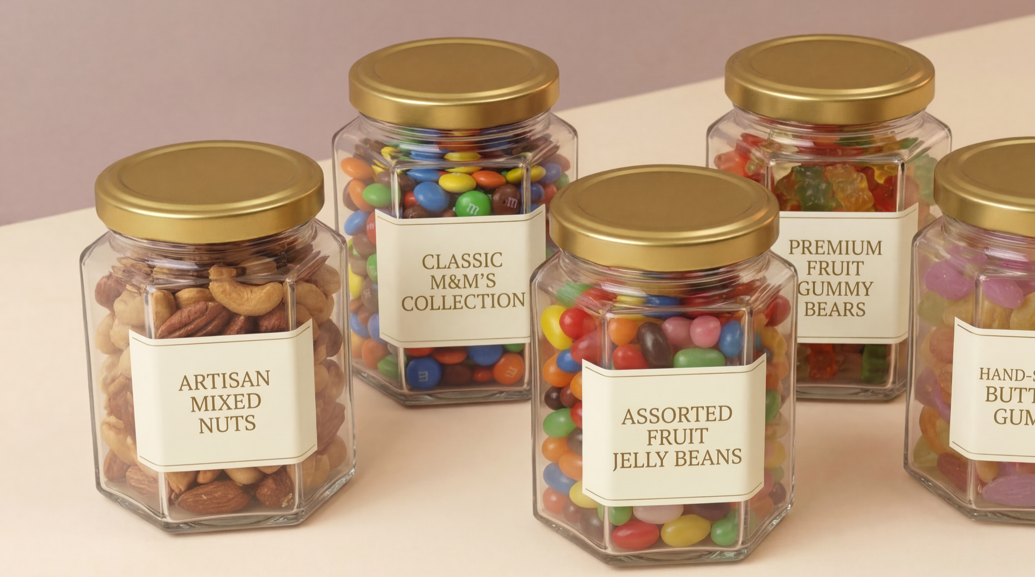 Five glass jars with gold lids containing different types of candy and nuts, labeled as artisan mixed nuts, classic M&M's collection, assorted fruit jelly beans, premium fruit gummy bears, and hand-dipped butter gummies.