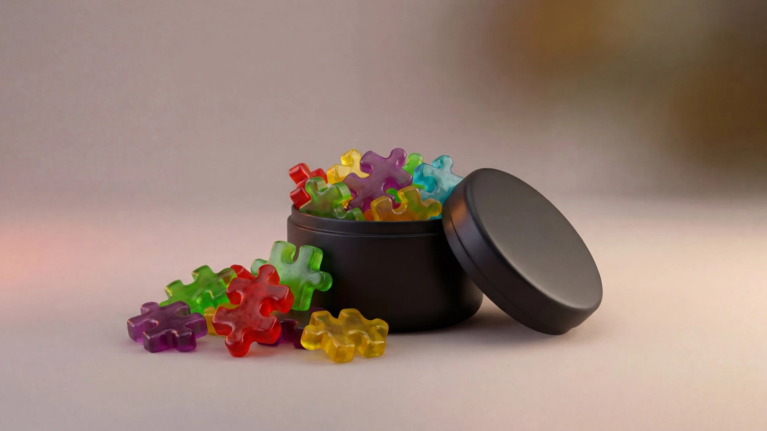 Colorful puzzle pieces spilling out of a black container with a rounded lid, with some pieces on a flat surface.