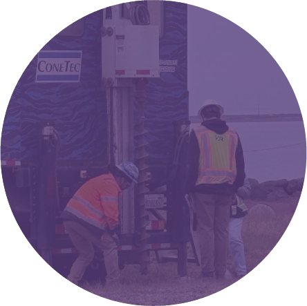 Construction workers operating heavy machinery outdoors, wearing safety vests and helmets.