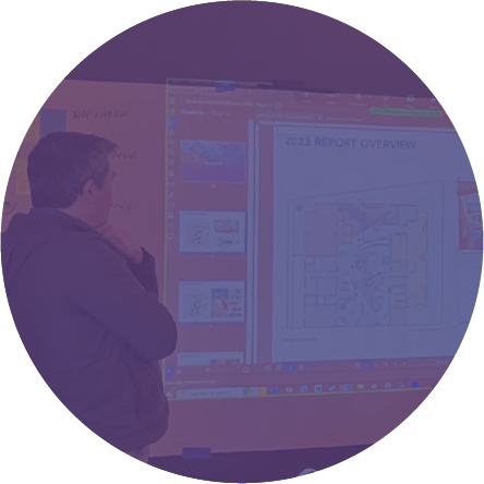 Person looking at a large presentation screen displaying a floor plan and a report overview.