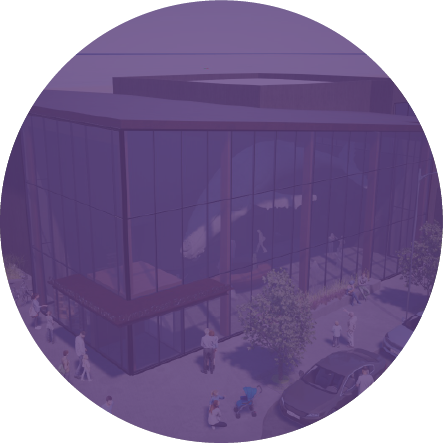 Modern glass building with people walking outside and cars parked nearby.