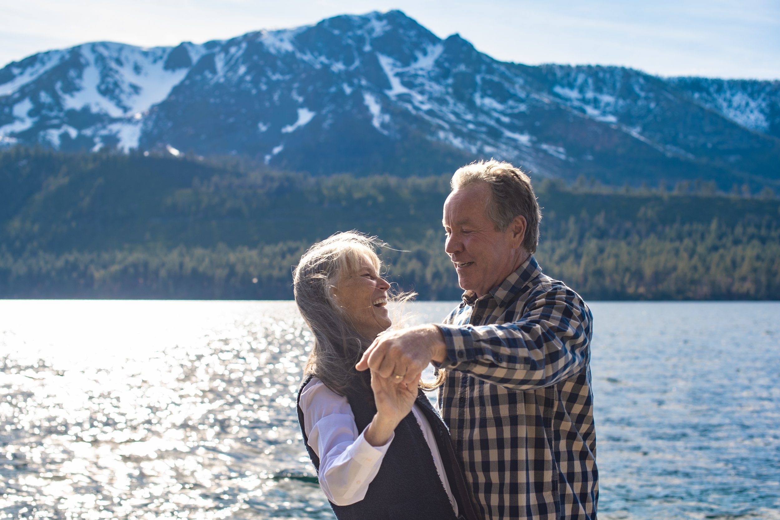 Older couple dancing and laughing with lake and mountains in the background