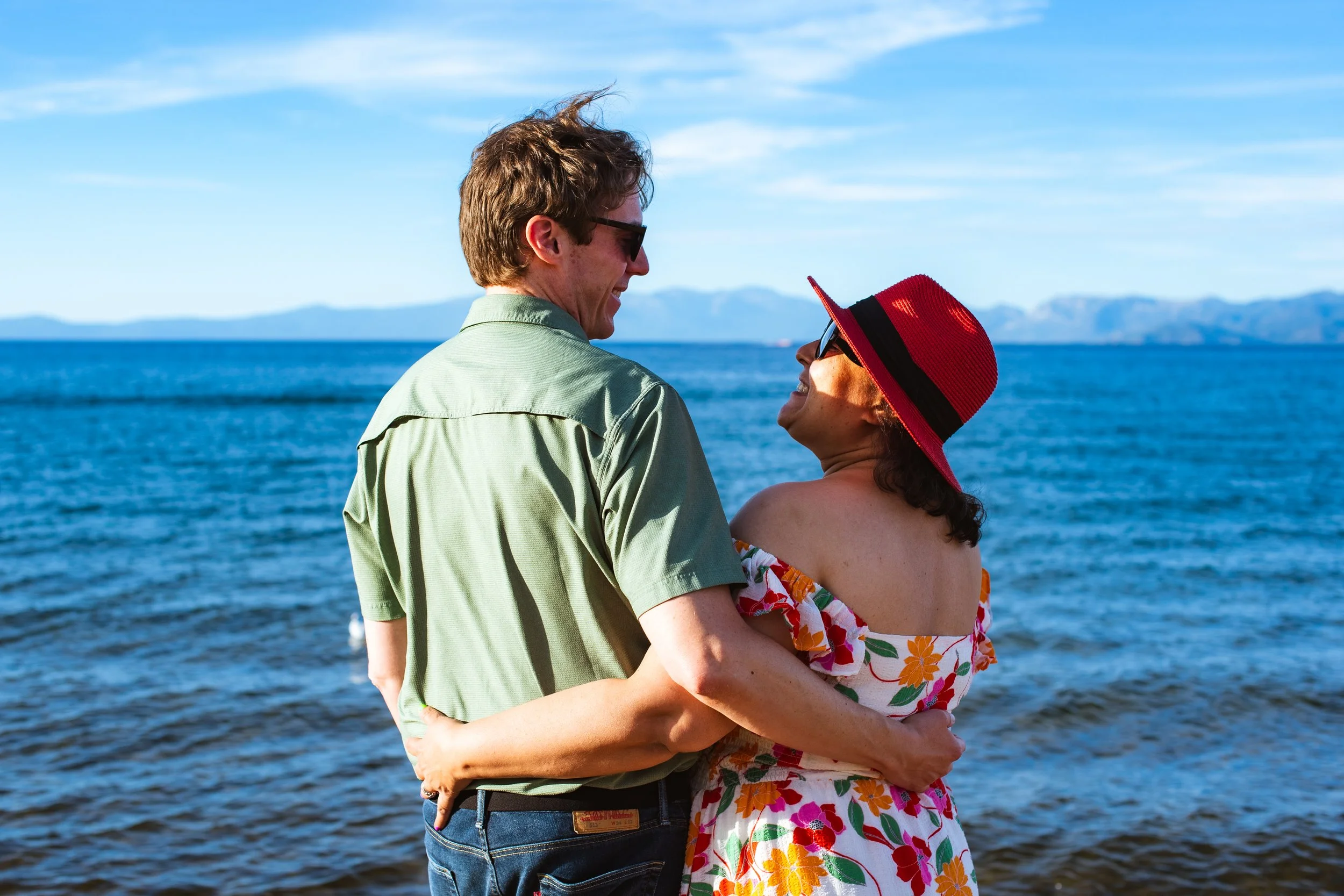 Couple smiling at each other standing in front of Lake Tahoe