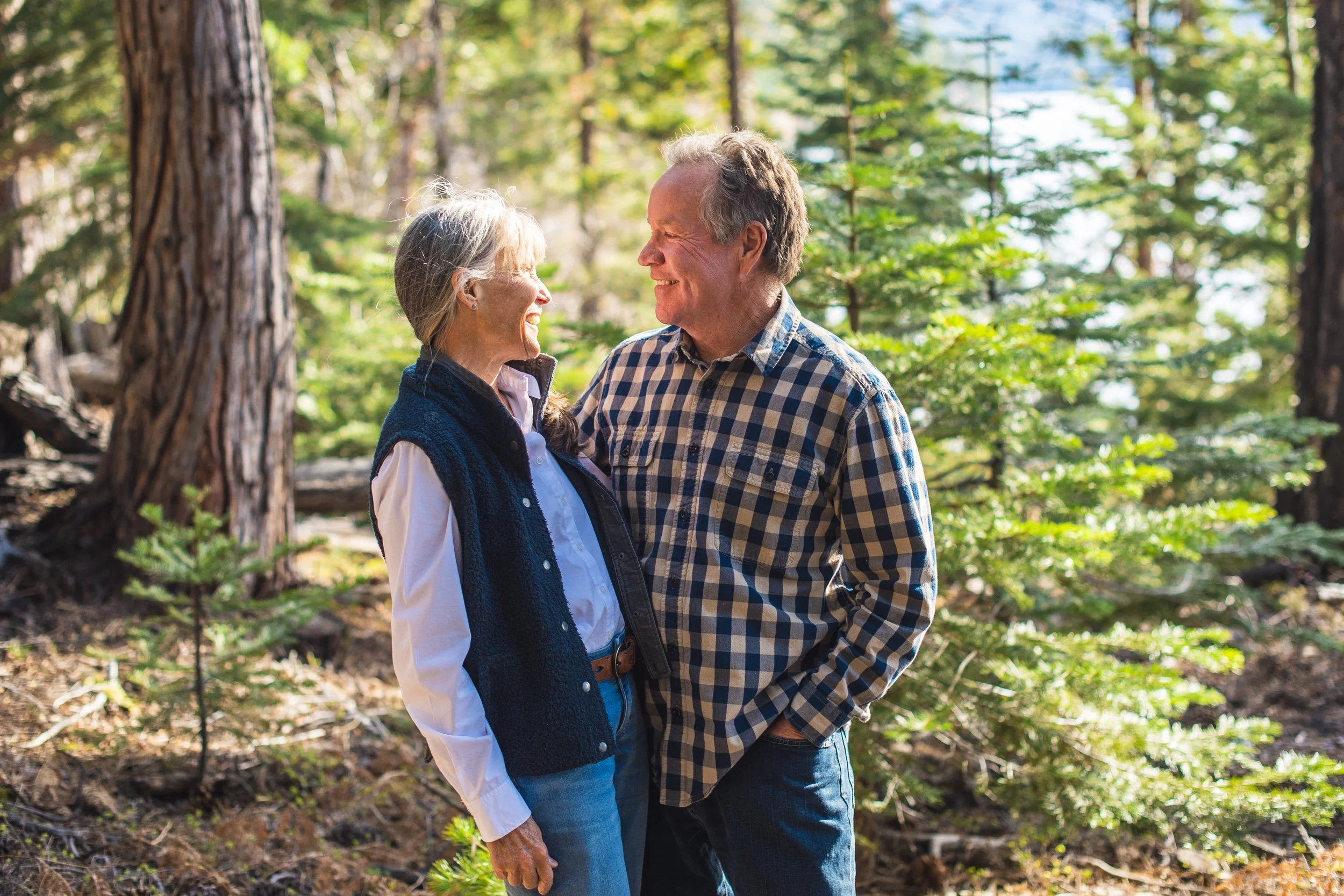 Couple standing a pine forest smiling at each other